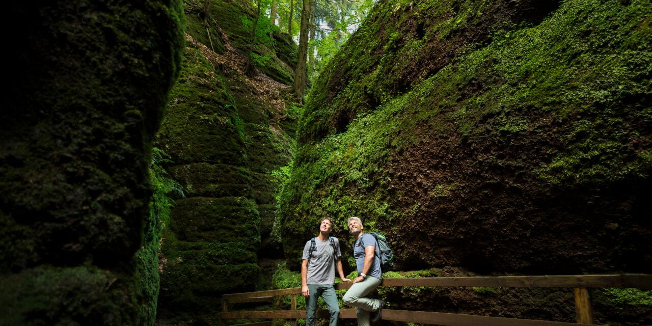 Zwei Wanderer zwischen hohen Felswänden in der Drachenschlucht bei Eisenach